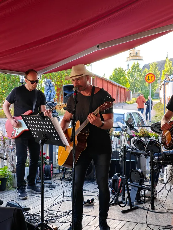 Sångaren i hatt sjunger och spelar akustisk gitarr